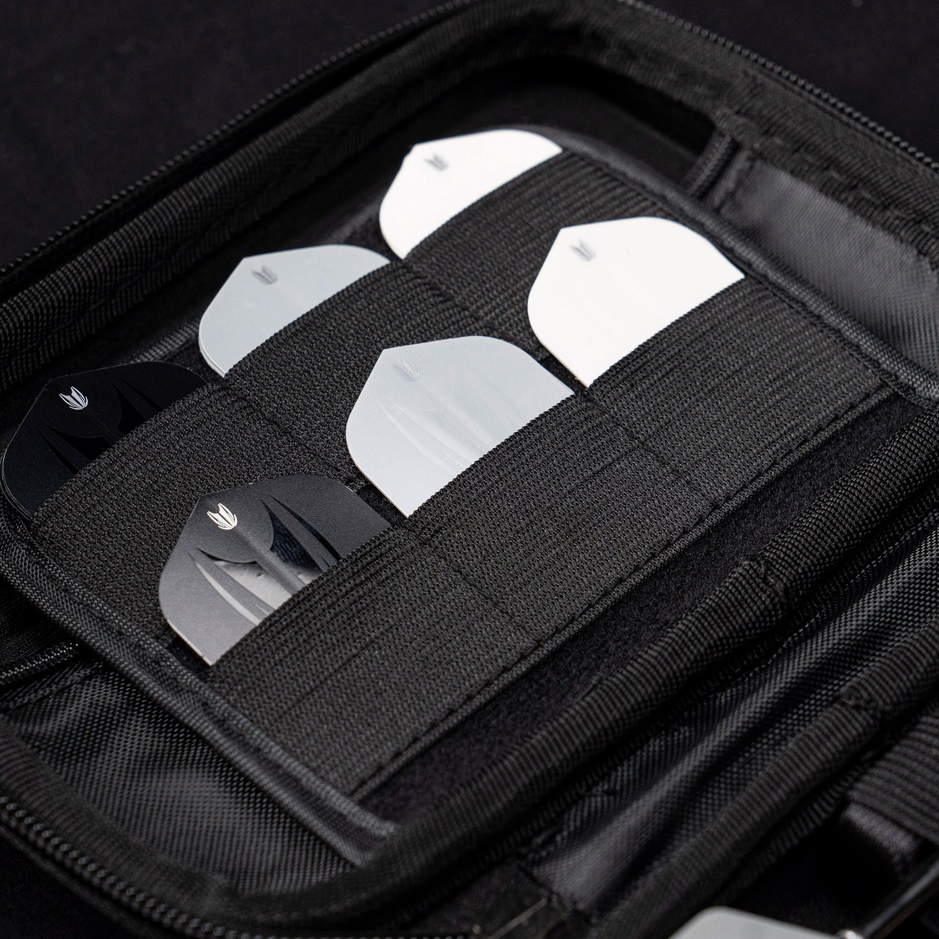 Takoma Ghost Series Raymond Van Barneveld dart case Das Bild zeigt das Target Takoma Bolide Dartcase, in dem mehrere Dart-Flights ordentlich in elastischen Halterungen verstaut sind. Das Case ist schwarz und bietet sicheren Schutz für das Dartzubehör.