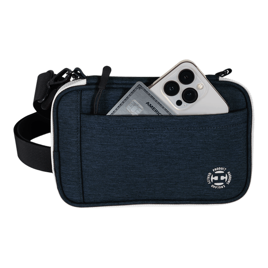 Harrows Smart Case XL dart wallet Eine blaue Tasche mit Vorderfach enthält ein Smartphone und eine Kreditkarte. Am unteren Rand der Tasche befindet sich ein rundes weißes Logo.