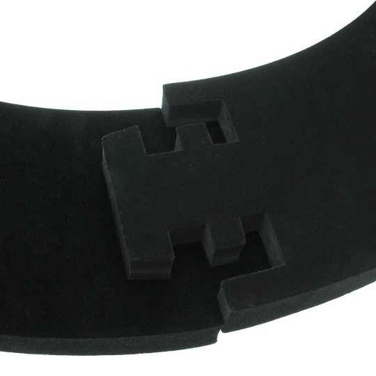 DBS3S_Bulls_Quarterback_Surround_Schwarz_4 Das Bild zeigt ein Produkt namens „Quarterback Surround“. Es handelt sich um ein gebogenes, schwarzes Schaumstoffelement mit geometrischen Aussparungen.