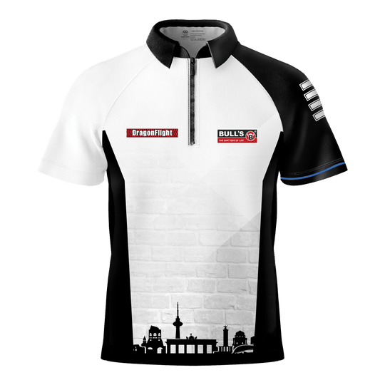 Bulls Martin Schindler The Wall dart shirt Das Bild zeigt das Bulls Martin Schindler The Wall Dartshirt mit einem schwarz-weißen Design und kurzen Ärmeln. Auf der Vorderseite befinden sich Logos und eine stilisierte Stadtsilhouette am unteren Rand.