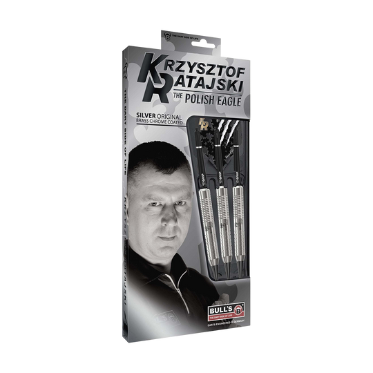 Auf dem Bild ist eine Verpackung der "Bulls Krzysztof Ratajski Brass Silver Softdarts - 18g" zu sehen. Die Verpackung zeigt drei silberfarbene Softdarts und ein Porträt eines Mannes.